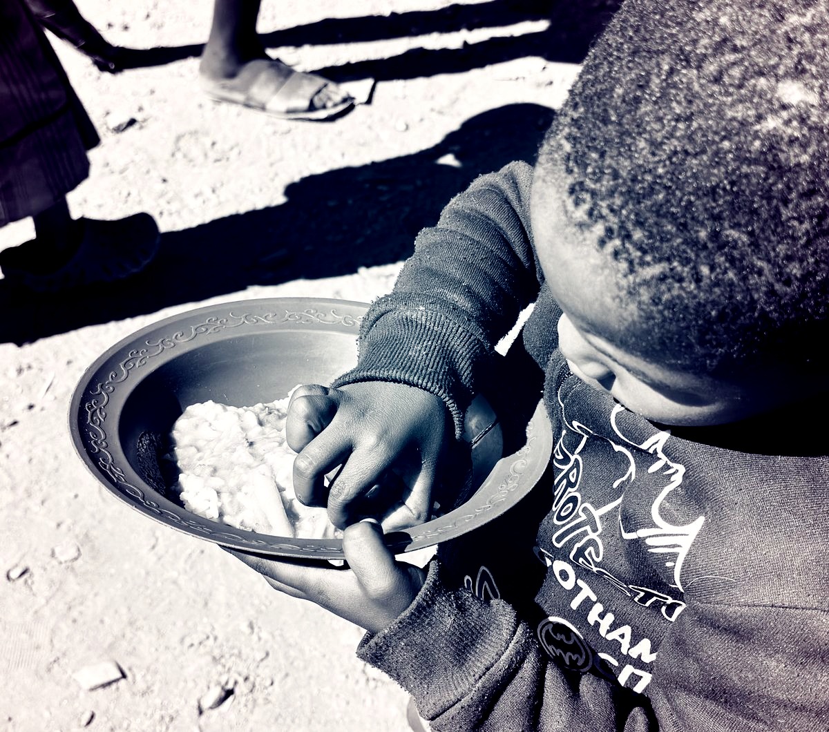 A child holding a bowl of food received at a Lechem soup kitchen